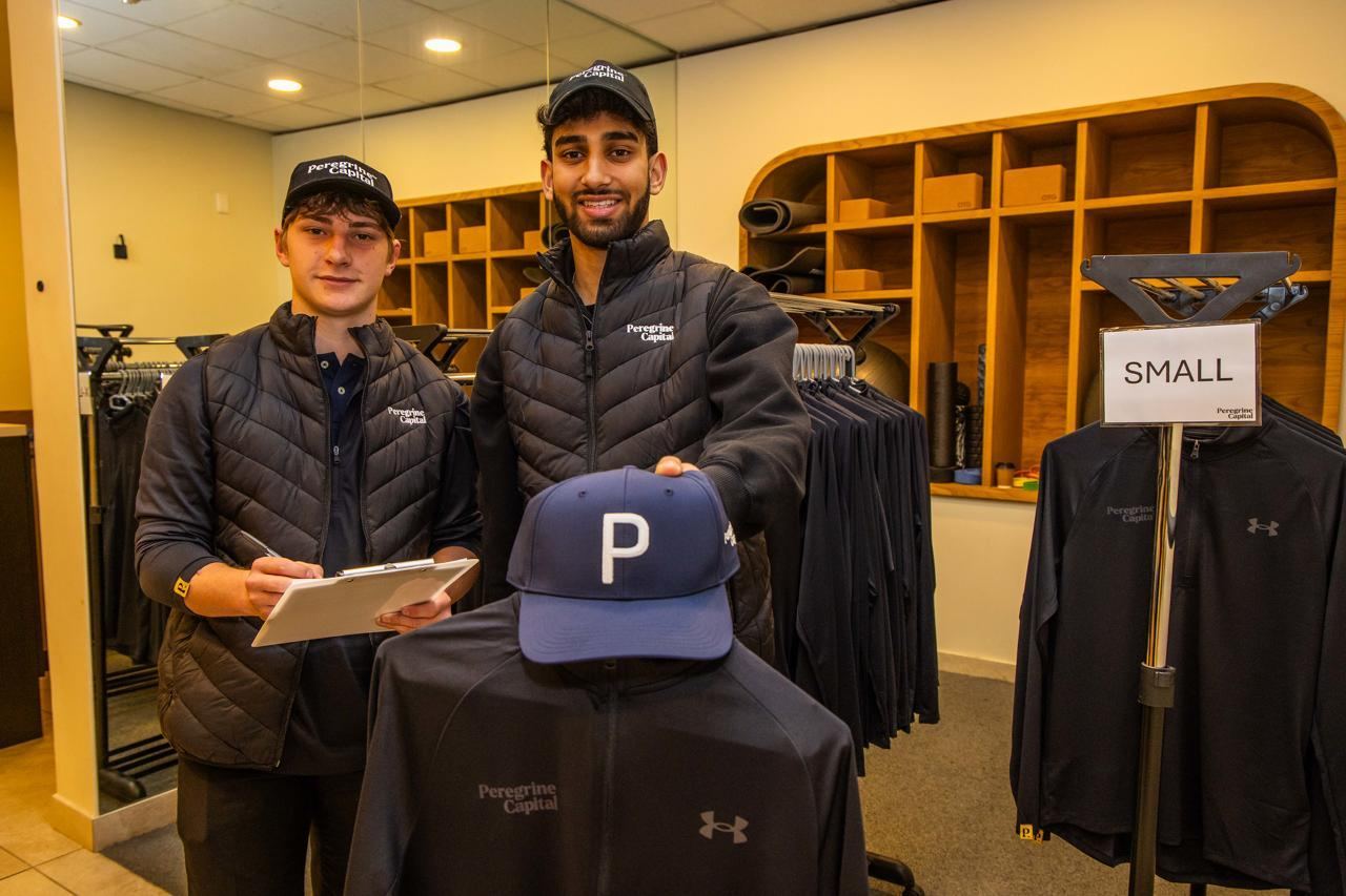 Two StuSta staff with branded merchandise